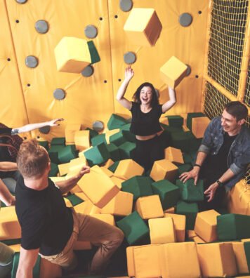 The company is a young woman who has fun with soft blocks on a children's playground in a trampoline center